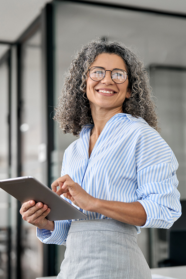 Older businesswoman smiling and holding tablet