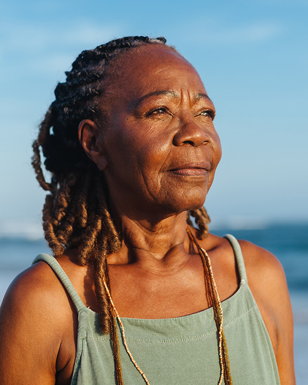 Calm elderly woman on beach looking to the sunset